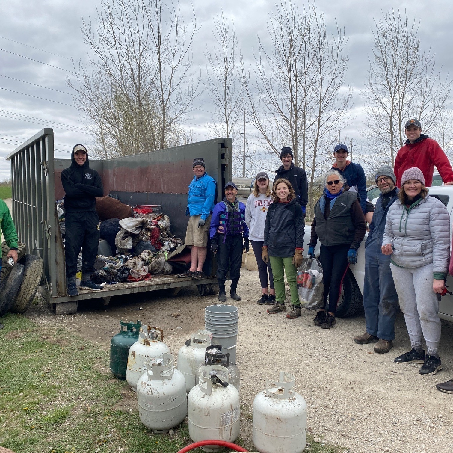 Volunteers with trash next to the trash receptacle